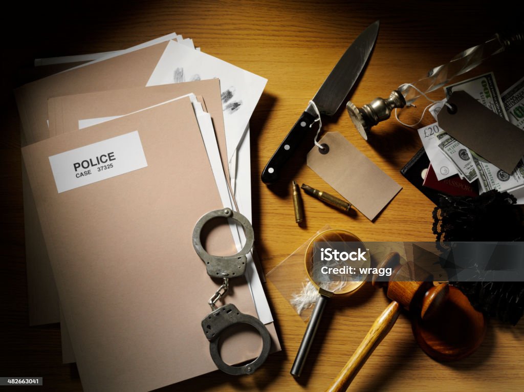 Police paper files on a wooden desk, overhead view with evidence from a crime.